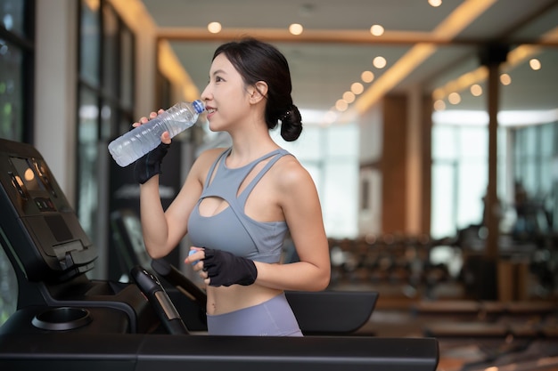 Une femme boit de l'eau d'une bouteille en plastique après l'entraînement