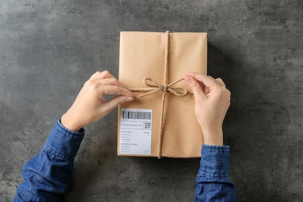 Femme avec boîte-cadeau colis sur fond gris