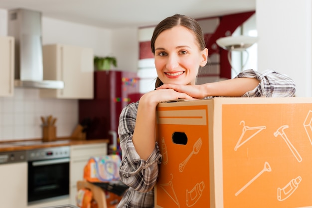 Femme avec boîte de déménagement dans sa maison