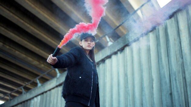 Femme avec une bombe fumigène à la main en regardant la caméra