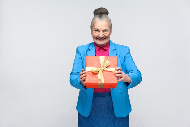 Femme de bonheur tenant une boîte-cadeau rouge et souriant à pleines dents