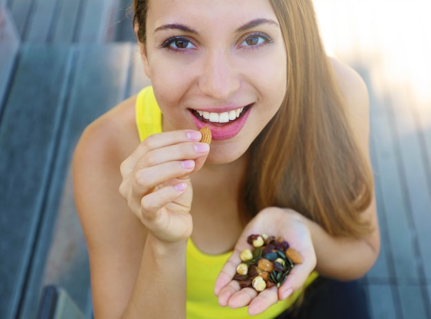 Femme en bonne santé de remise en forme, manger un mélange de graines de noix fruits secs en plein air.