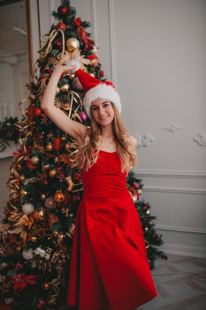 Photo femme en bonnet de noel avec arbre de noël