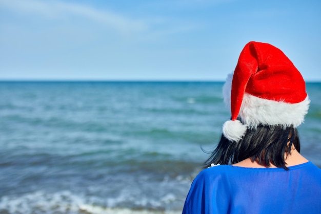 Femme en bonnet de noel debout sur la plage