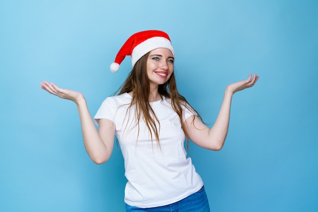 La femme en bonnet de Noel est très heureuse et heureuse, elle montre un geste de victoire, elle a obtenu le résultat le ...