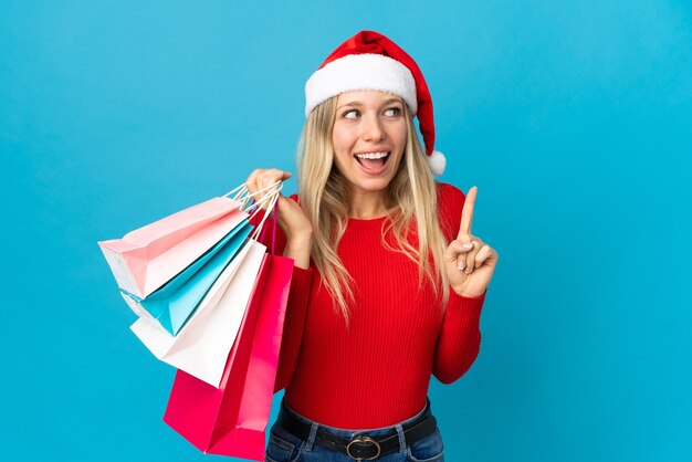 femme avec bonnet de noel tenant des sacs à provisions