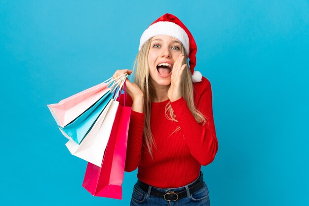 femme avec bonnet de noel tenant des sacs à provisions