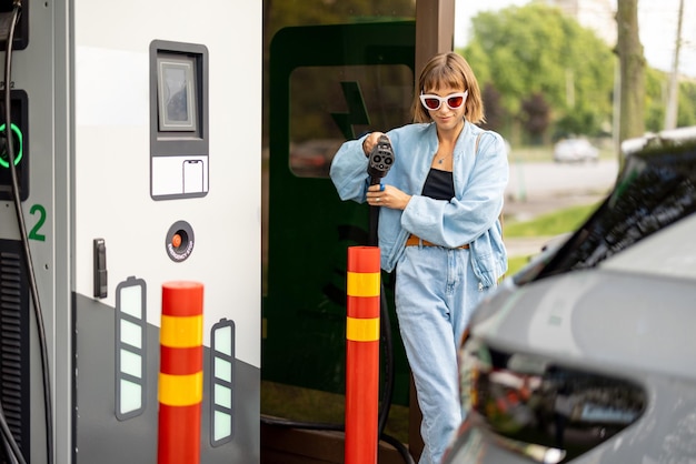 Femme sur borne de recharge pour voitures électriques