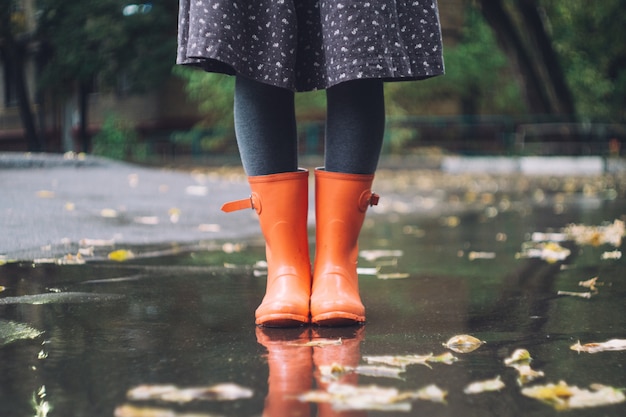 Une femme en bottes de caoutchouc rose vif (bottes en caoutchouc) sous la pluie. Concept d'automne