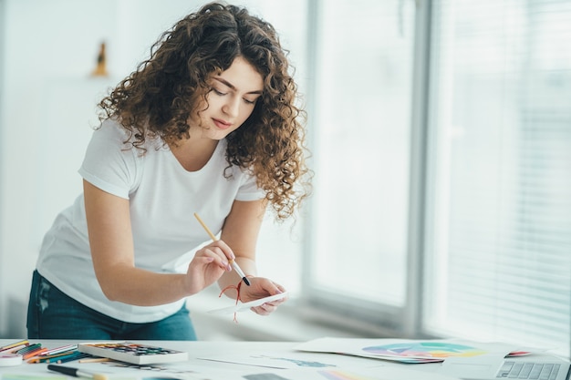 La femme bouclée peignant une image à la table