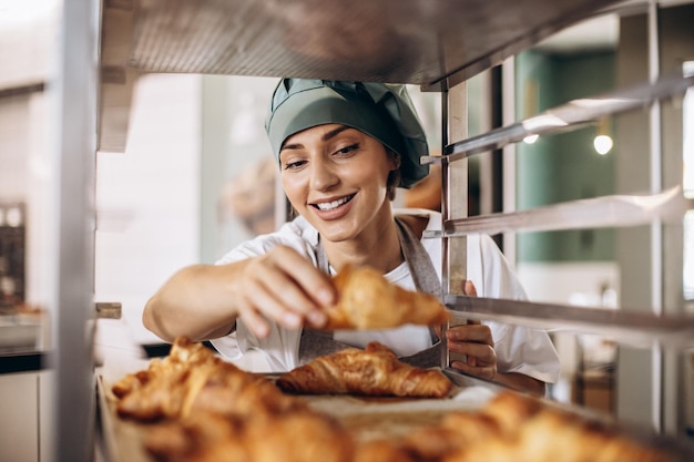 Femme boulangère à la cuisine tenant un croissant