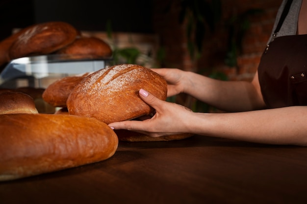 Photo femme boulangère avec du pain cuit dans la pâtisserie