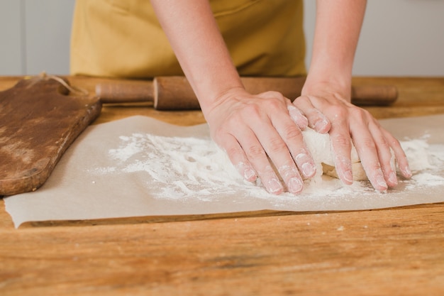 Une femme boulangère ou pâtissière pétrit la pâte. Fermer.