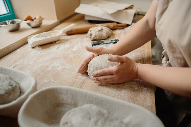 Femme boulangère pétrir une pâte dans une boulangerie