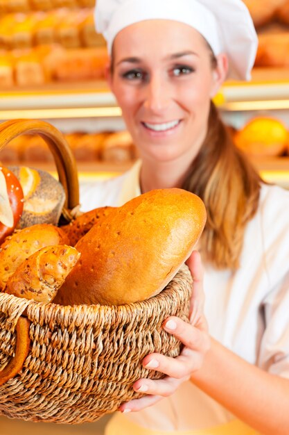 Femme boulangère vendant du pain par panier en boulangerie