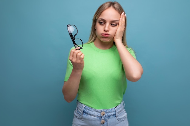 Femme bouleversée tenant des lunettes et tenant sa tête sur fond bleu