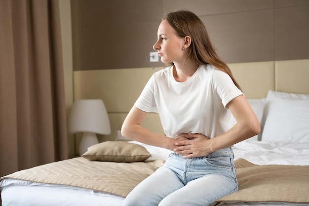 Une femme bouleversée tenant le ventre avec les mains a de mauvais maux d'estomac