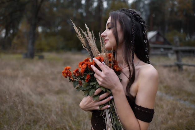 Femme avec un bouquet de fleurs dans un champ, elle les tient près de sa poitrine en appréciant leur parfum