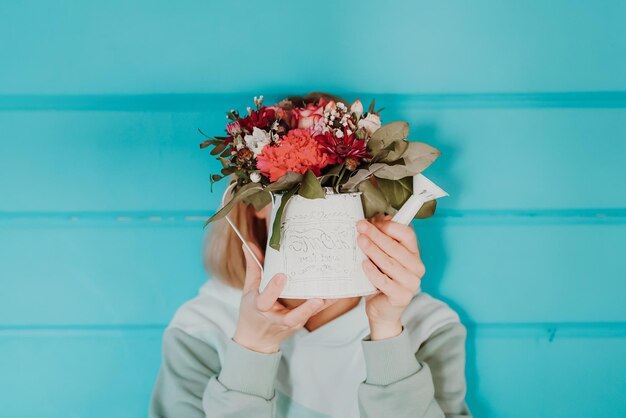 Femme avec un bouquet de fleurs sur fond bleu