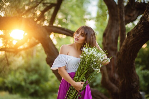 La femme avec un bouquet des fleurs touche ses cheveux