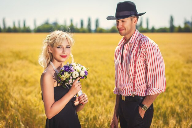 Femme avec bouquet et homme sur un beau champ de blé