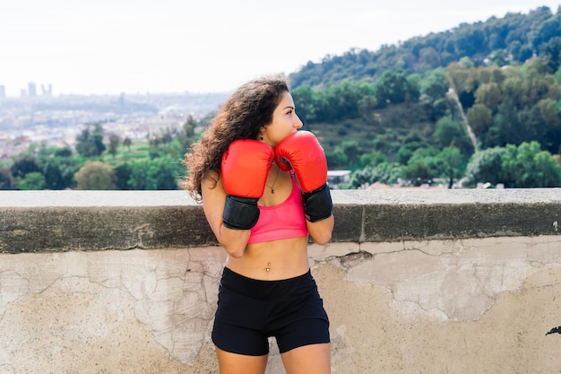Une femme boxeur s'entraînant en plein air - ville et nature en arrière-plan