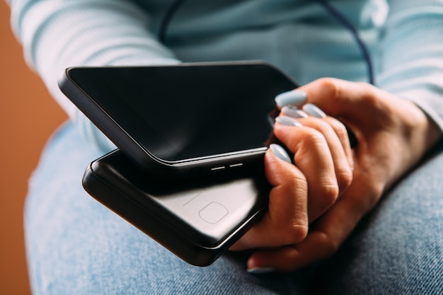 La femme a branché le chargeur avec le téléphone au bureau ou à la maison. Banque de puissance.