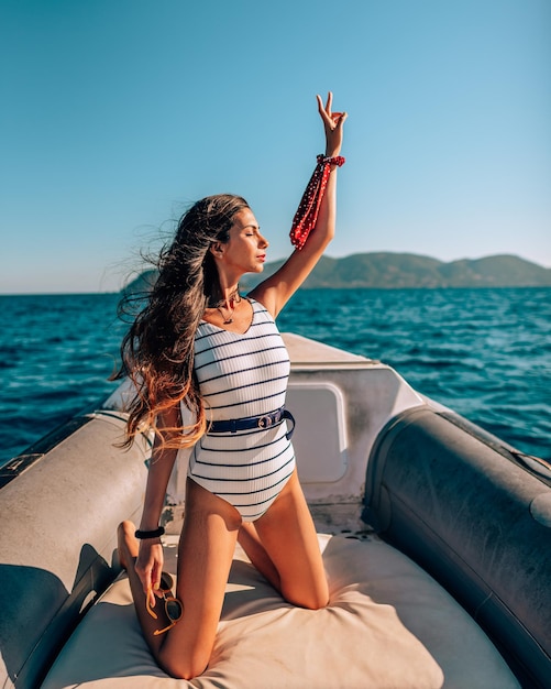Femme avec le bras levé agenouillée dans un navire nautique en mer contre le ciel