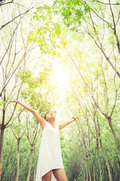 Photo femme avec les bras tendus debout contre les arbres dans la forêt