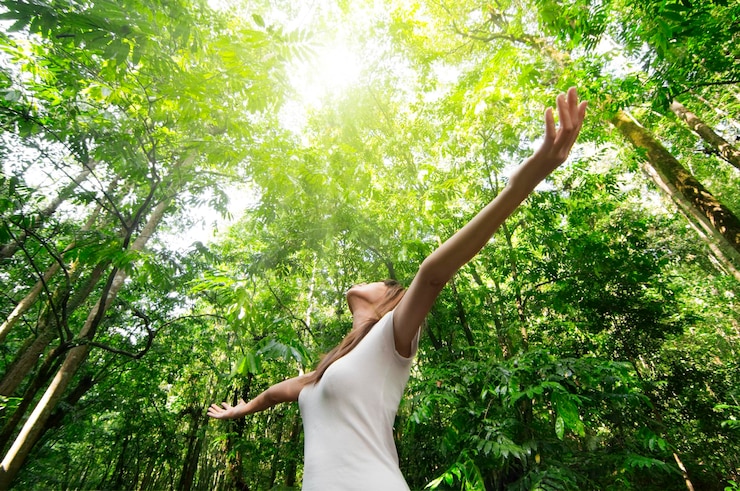 Photo femme avec les bras tendus debout contre les arbres