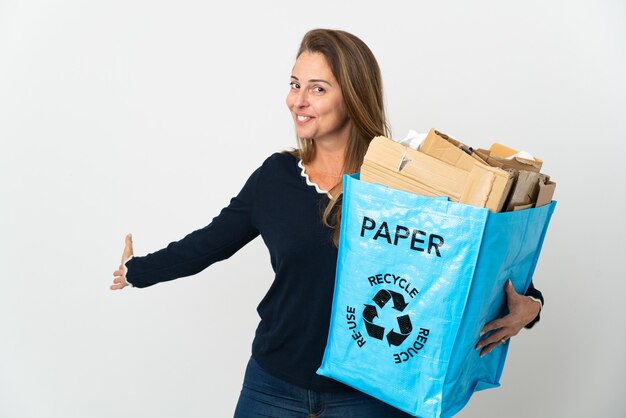 Femme brésilienne d'âge moyen tenant un sac de recyclage plein de papier à recycler isolé