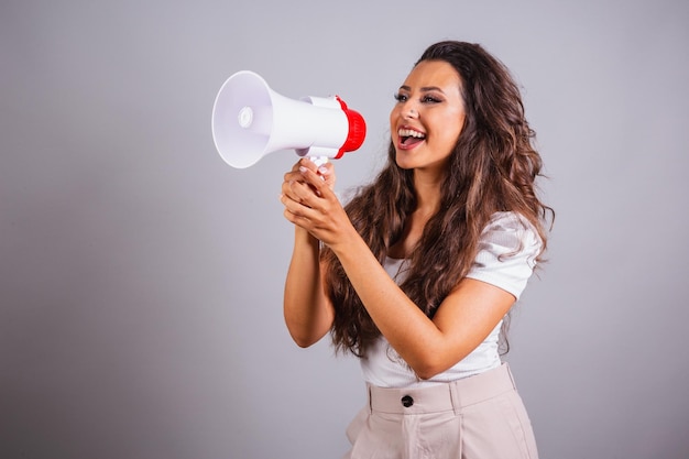 Femme brésilienne cheveux bruns tenant un mégaphone annonçant une réduction de promotion criant et appelant