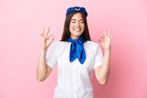 Femme brésilienne d'hôtesse d'avion isolée sur fond rose dans une pose zen