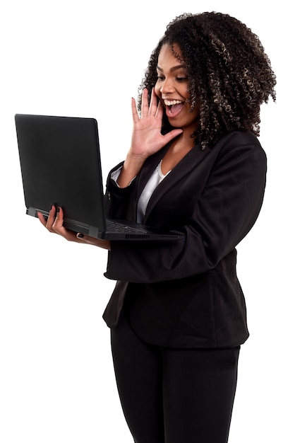 Femme brésilienne noire joyeuse et souriante isolée sur blanc, travaillant avec un ordinateur portable.