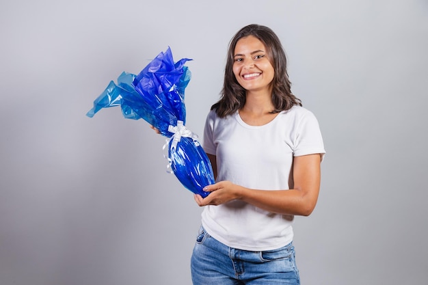 Femme brésilienne Pâques souriant joyeusement tenant un oeuf de Pâques en chocolat