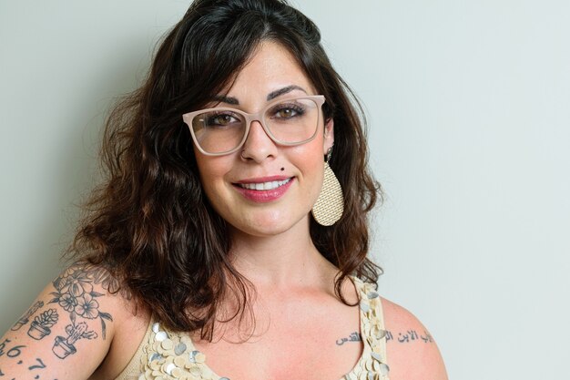 Femme brésilienne portant des lunettes, tatouée et souriante