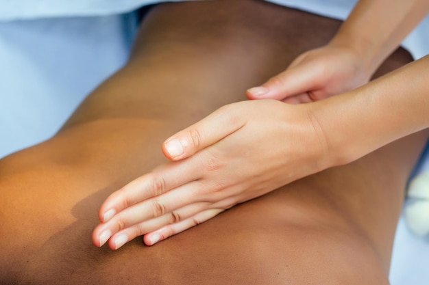 Femme brésilienne se masser le dos et les épaules dans un spa extérieur centre ayurvédique en Inde fond tropical vert