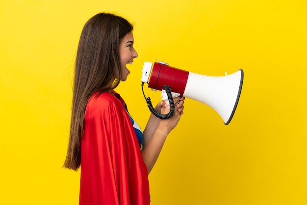 Femme brésilienne de super héros isolée sur fond jaune criant à travers un mégaphone