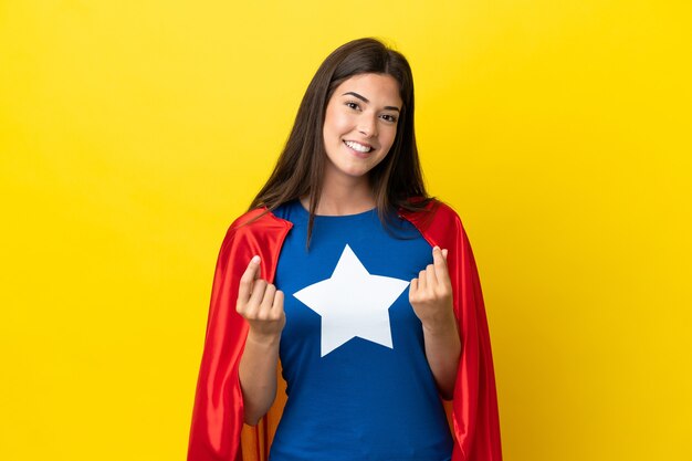 Femme brésilienne de super héros isolée sur fond jaune faisant un geste d'argent