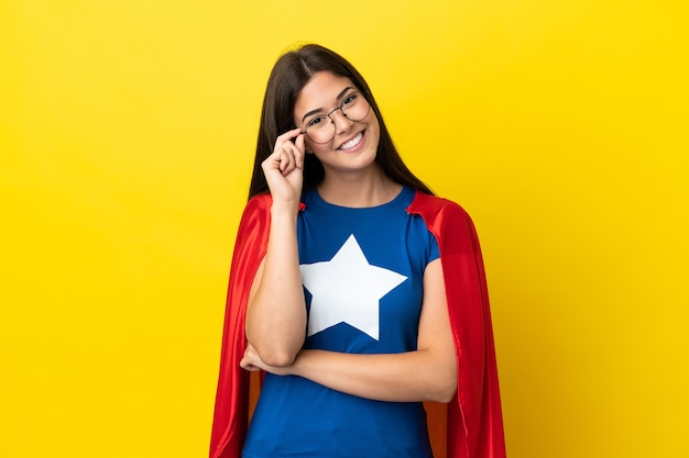 Femme brésilienne de super héros isolée sur fond jaune avec des lunettes et heureuse