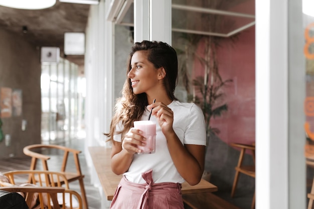 Femme bronzée en tenue lumineuse aime se détendre au café