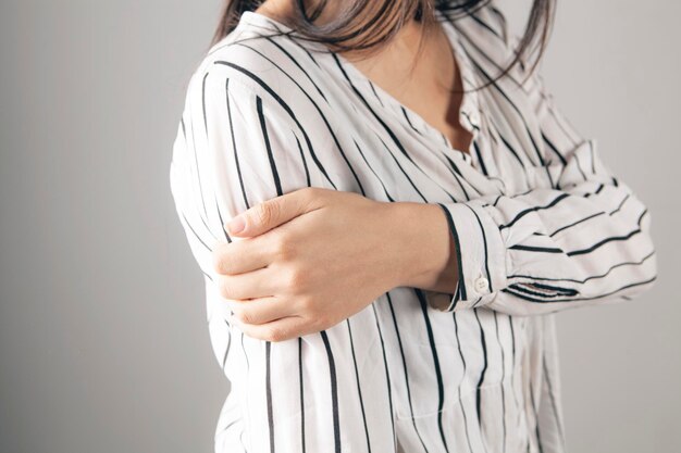 La femme a une brosse douloureuse sur un fond gris