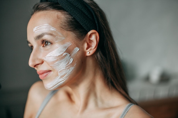 Femme brune de 30 ans avec de la crème sur son visage