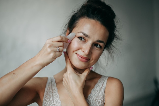 Femme brune de 30 ans faisant un massage du visage avec un grattoir à gouache