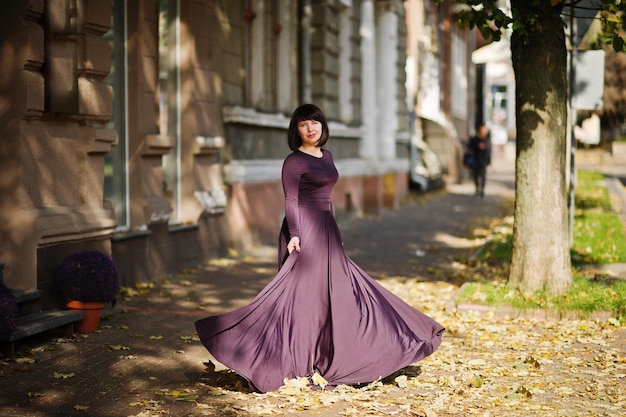 Femme brune adulte à robe violette sur fond d'automne automne