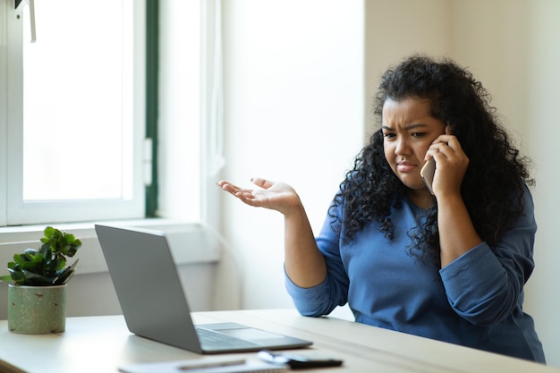 Une femme brune agacée travaillant à domicile a une conversation téléphonique