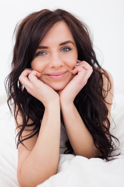 Femme brune, allongée sur sa couverture blanche