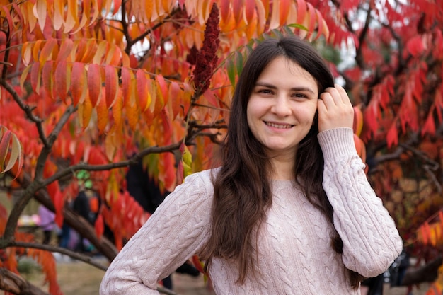 Une femme brune d'un an corrige ses longs cheveux et sourit