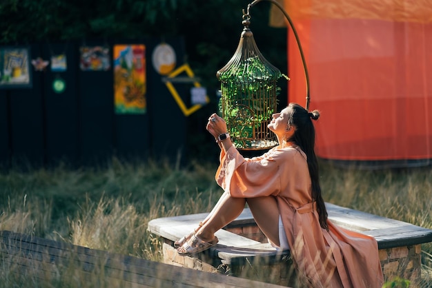 Femme brune assise sur un banc et profitant du coucher de soleil