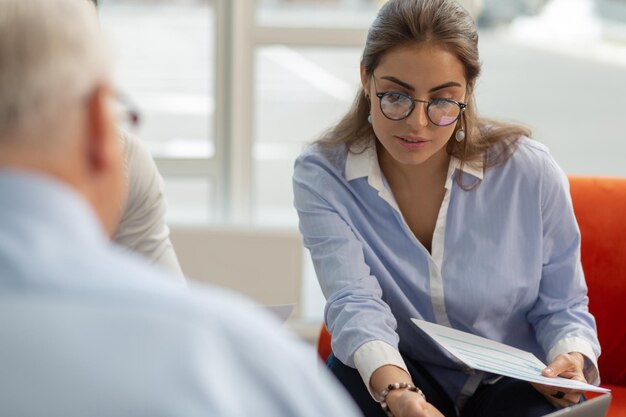 Femme brune attentive regardant pâle de documents